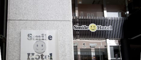 Une enseigne d’hôtel avec un logo représentant un visage souriant et du texte en japonais.