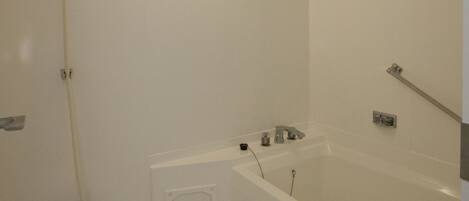 A modern bathroom with a bathtub, shower, and toilet.