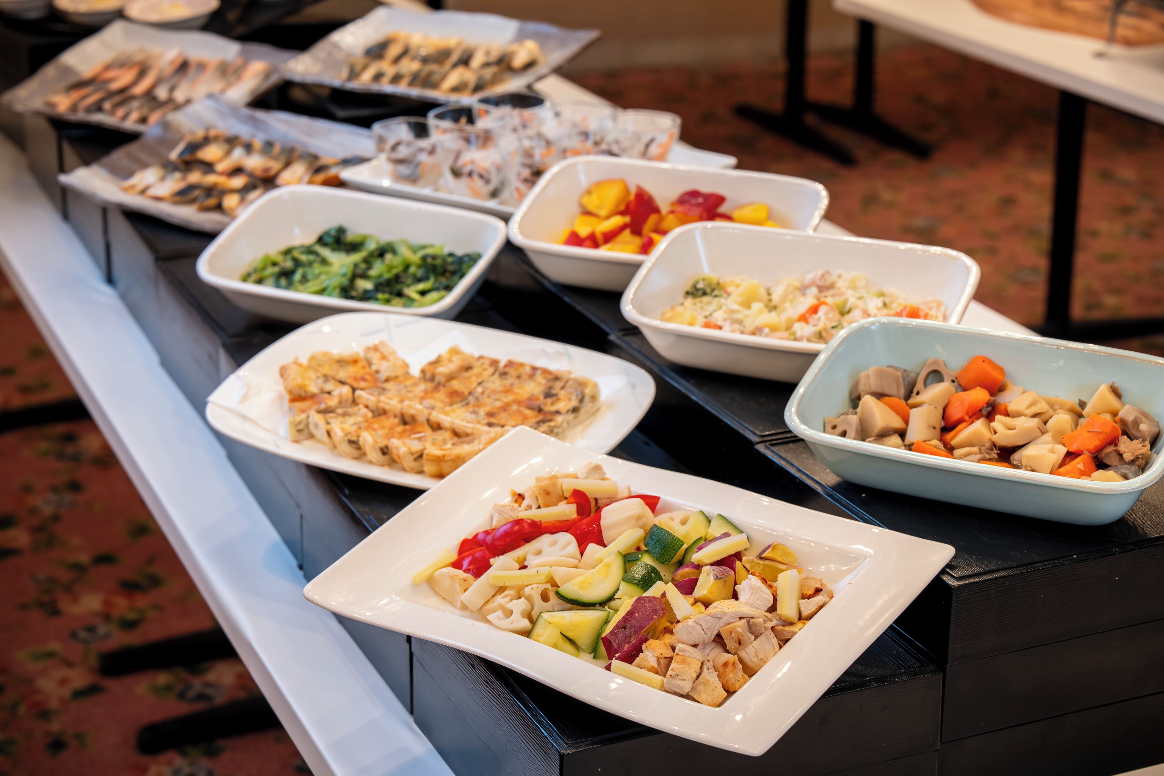 A buffet table with various dishes including salads, meats, and vegetables.