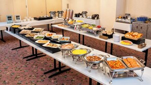 A buffet setup with various food items and serving utensils.