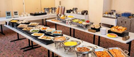 Una mesa de buffet con diversos alimentos y utensilios para servir.