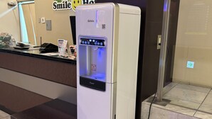 A white water dispenser with a digital display, placed on a wooden platform in a commercial setting.