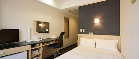 Quarto de hotel com cama, escrivaninha, cadeira e televisão.