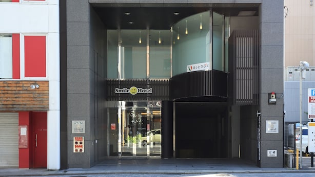 A hotel entrance with a modern design, glass doors, and a sign indicating it is the Smile Hotel.