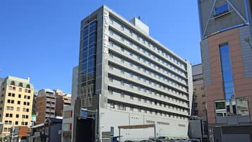 A multi-story hotel with a modern design, featuring a prominent entrance and a parking area in front.