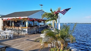 Eine Bar am Wasser mit Außenbereich, Blick auf das Wasser und amerikanischen Flaggen.