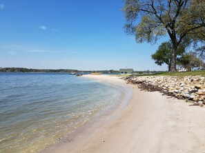 A beach with clear water, a rocky shoreline, and a building in the background. - Sandaway Suites & Beach (Oxford)