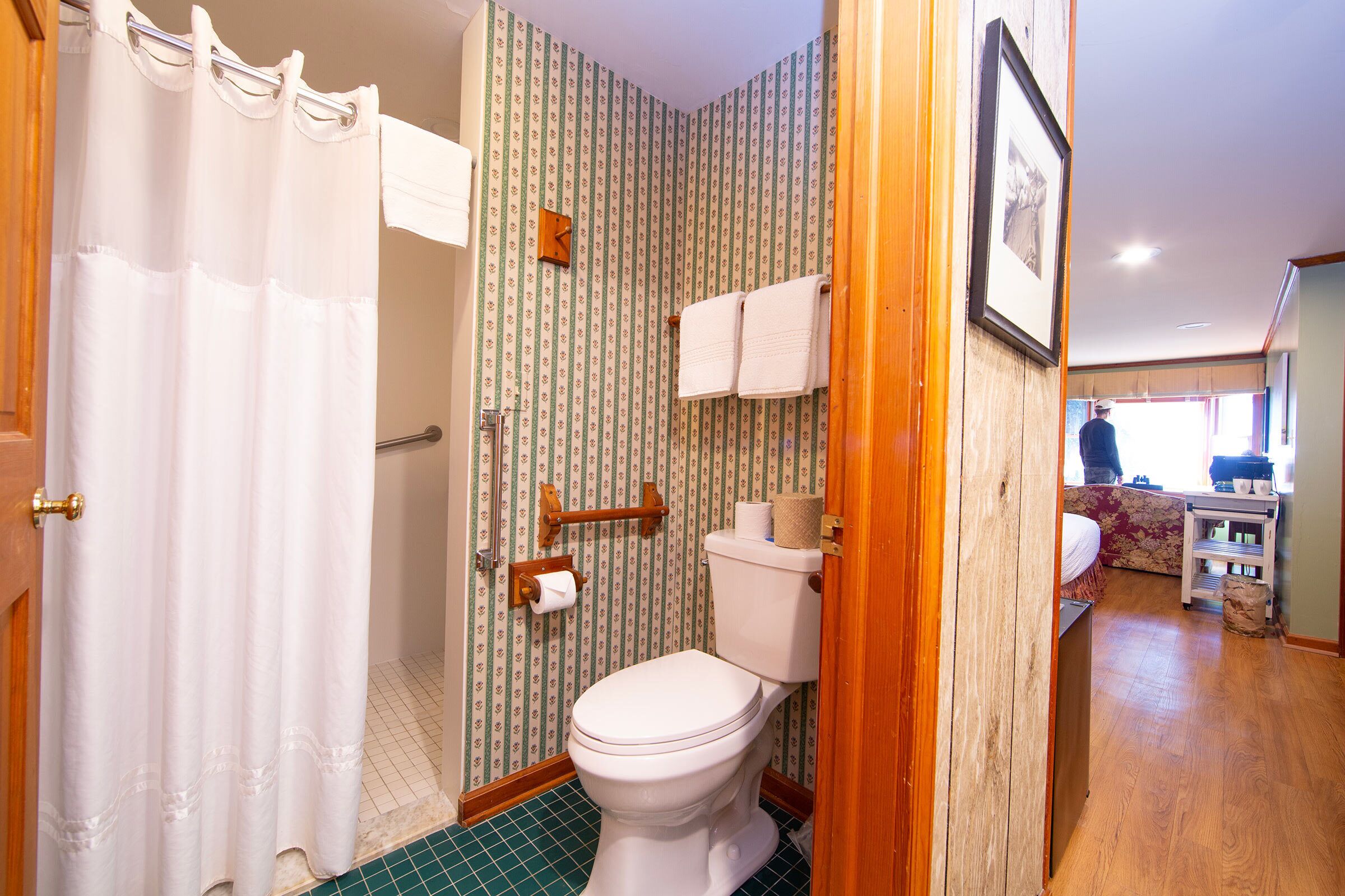 A bathroom with a toilet, shower curtain, and patterned wallpaper.