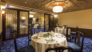 A dining area with round tables set for four, blue patterned carpet, and traditional decor. - Hilltop Hotel (Tokyo)