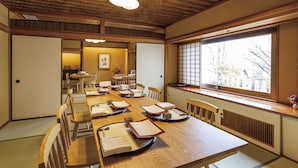 A traditional Japanese-style dining room with tatami mats, wooden furniture, and a large window offering a view of the outside. - Hilltop Hotel (Tokyo)