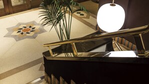 A staircase with a handrail, a patterned floor, and a potted plant. - Hilltop Hotel (Tokyo)