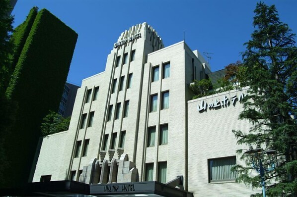 A modern hotel building with a prominent "Hilton" sign at the top. - Hilltop Hotel (Tokyo)