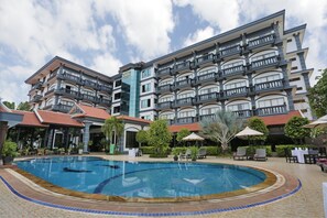 A hotel with a swimming pool, multiple balconies, and outdoor seating areas. - Lucky Angkor Hotel & Spa (Siem Reap)