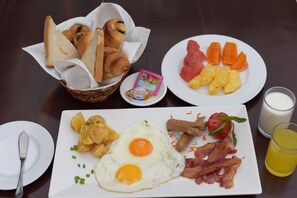 A breakfast plate with eggs, bacon, tomatoes, and a glass of orange juice. - Lucky Angkor Hotel & Spa (Siem Reap)