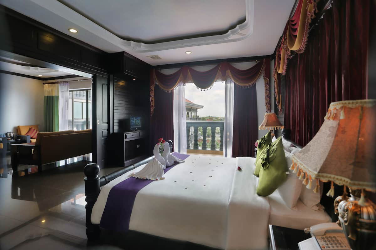 A hotel room with a bed, a desk, a lamp, and a view of the outside.