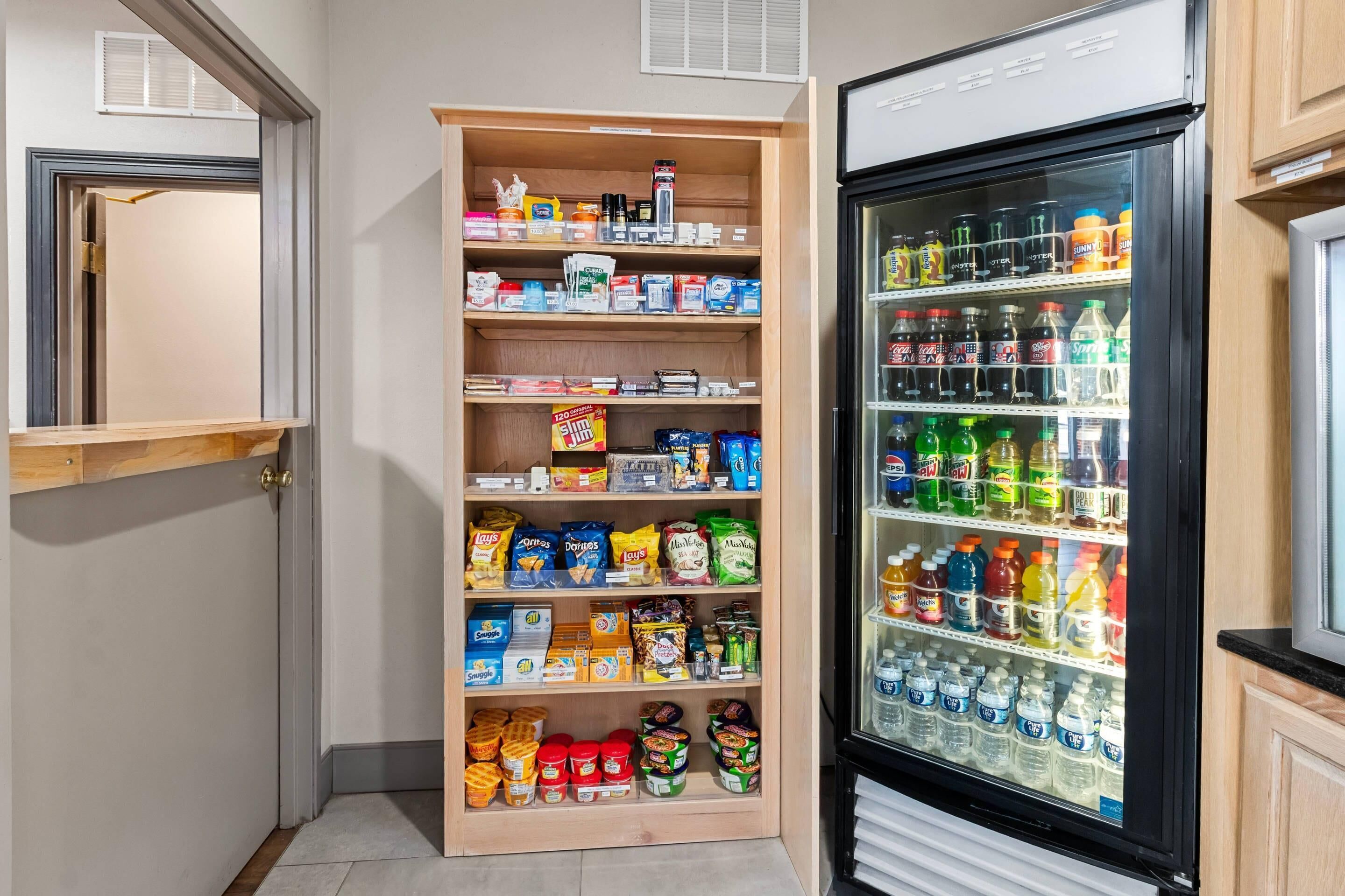 A kitchenette with a refrigerator stocked with beverages and a pantry with snacks and condiments.