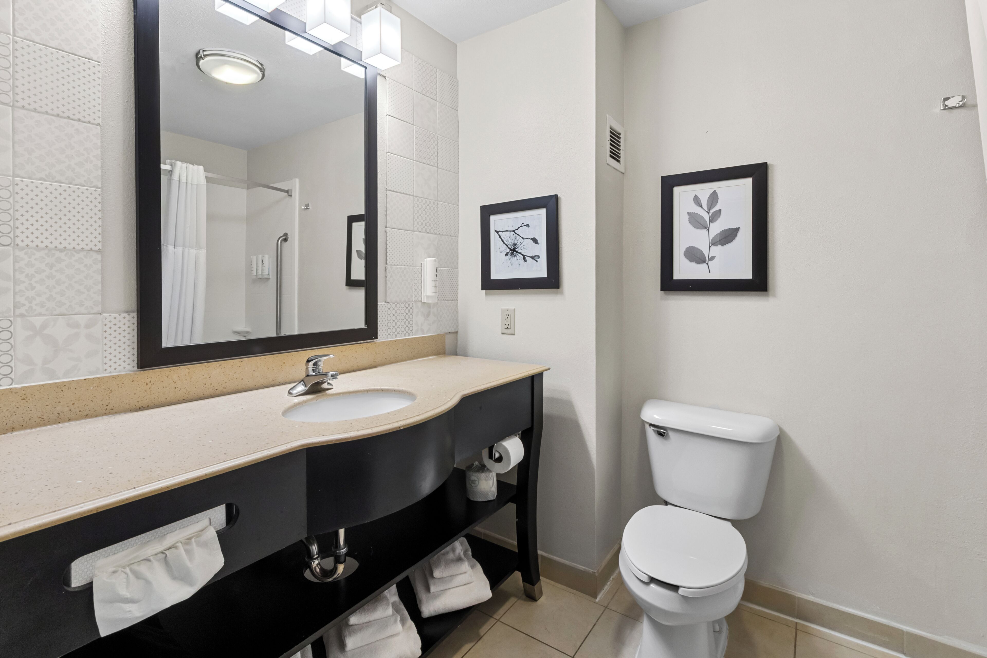 Un baño con lavabo, espejo, inodoro y toallero.
