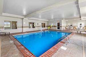 Una piscina interior con agua cristalina azul, paredes de azulejos y un borde de ladrillo.