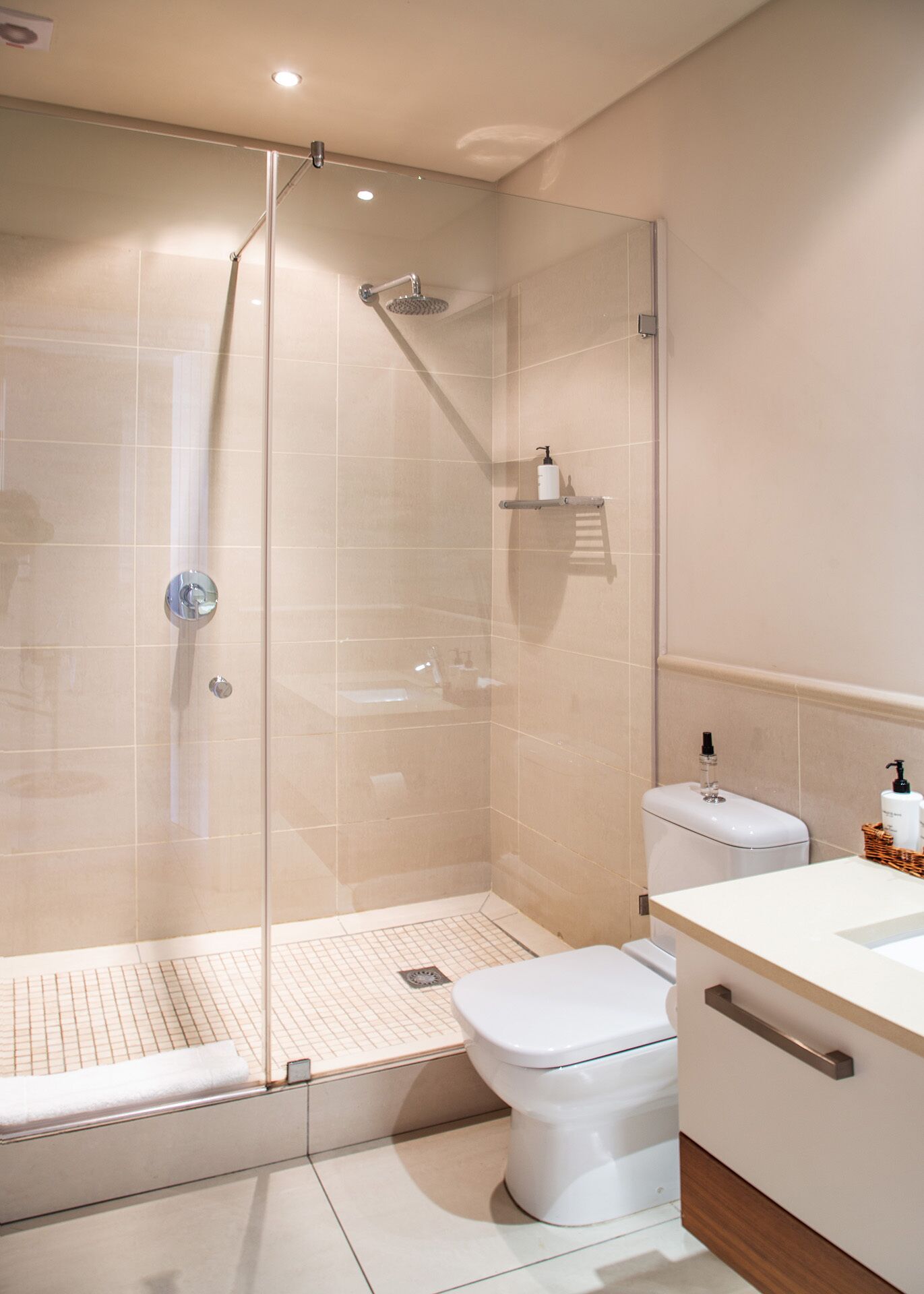 A modern bathroom with a glass-enclosed shower, a white toilet, and a sink with a wooden countertop.