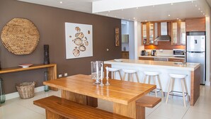 Una cucina moderna con isola centrale, panche in legno e un grande arazzo tessuto.