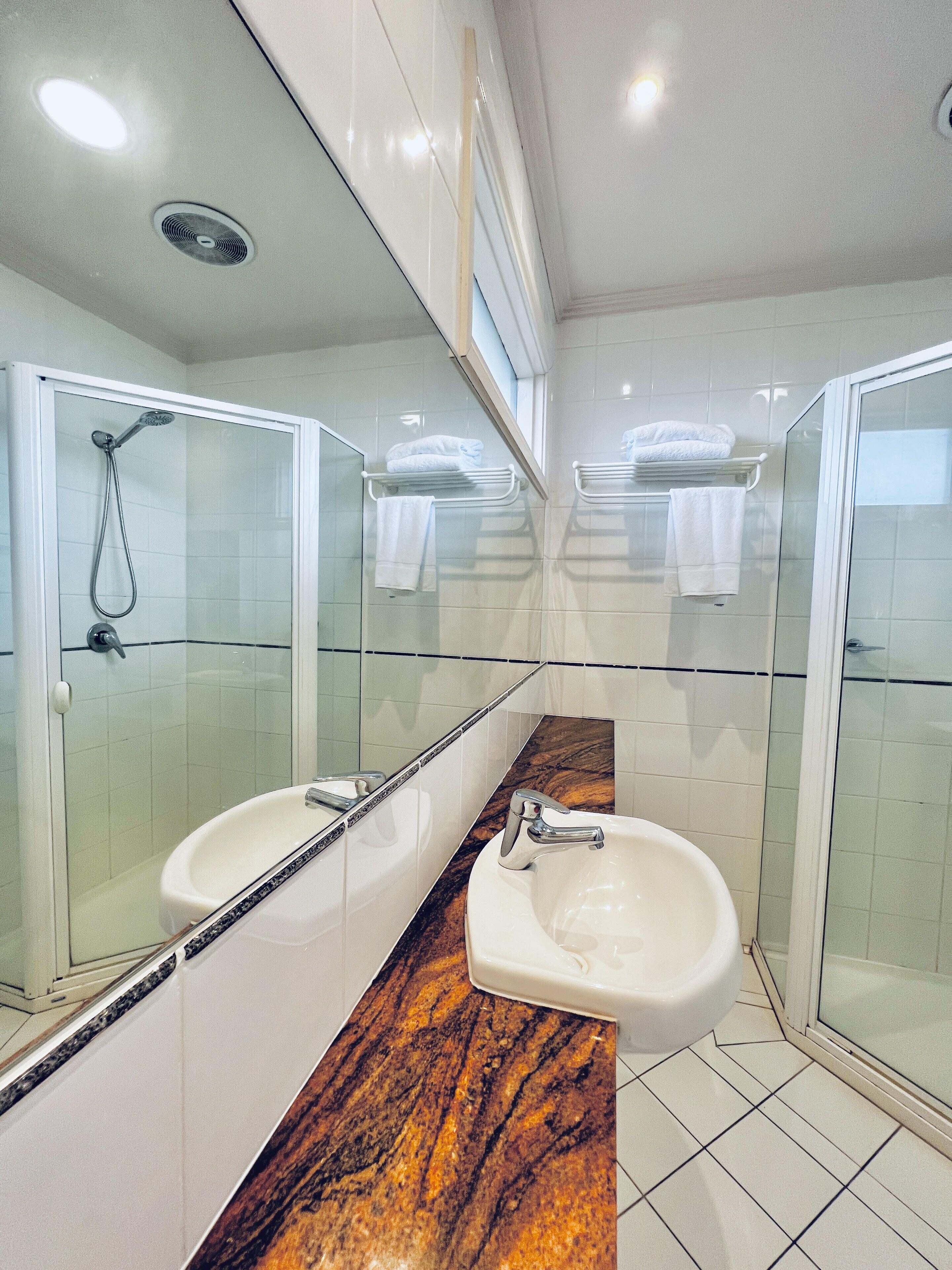 Un baño moderno con dos lavamanos, cabina de ducha de cristal y encimera de mármol.