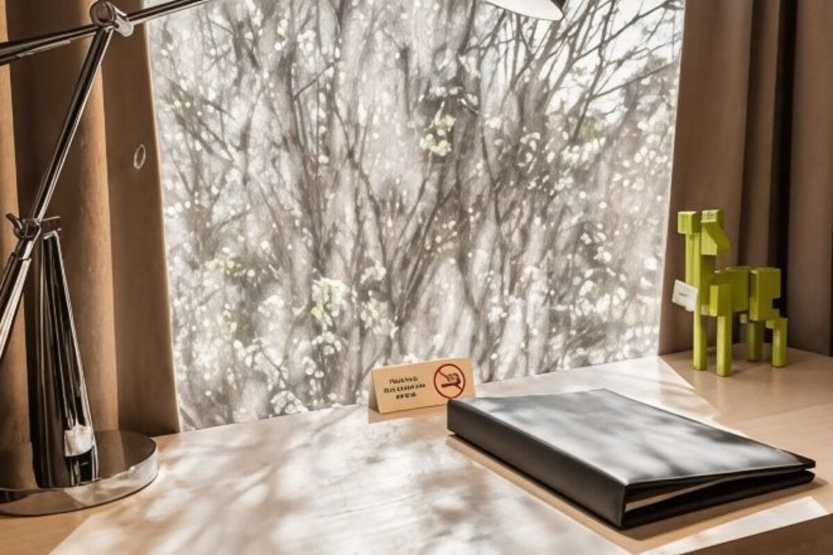 A desk with a lamp, a notebook, a sign with a prohibition symbol, and a green chair.
