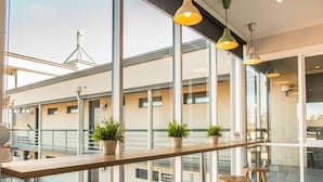 A modern interior with large windows, wooden stools, and potted plants.