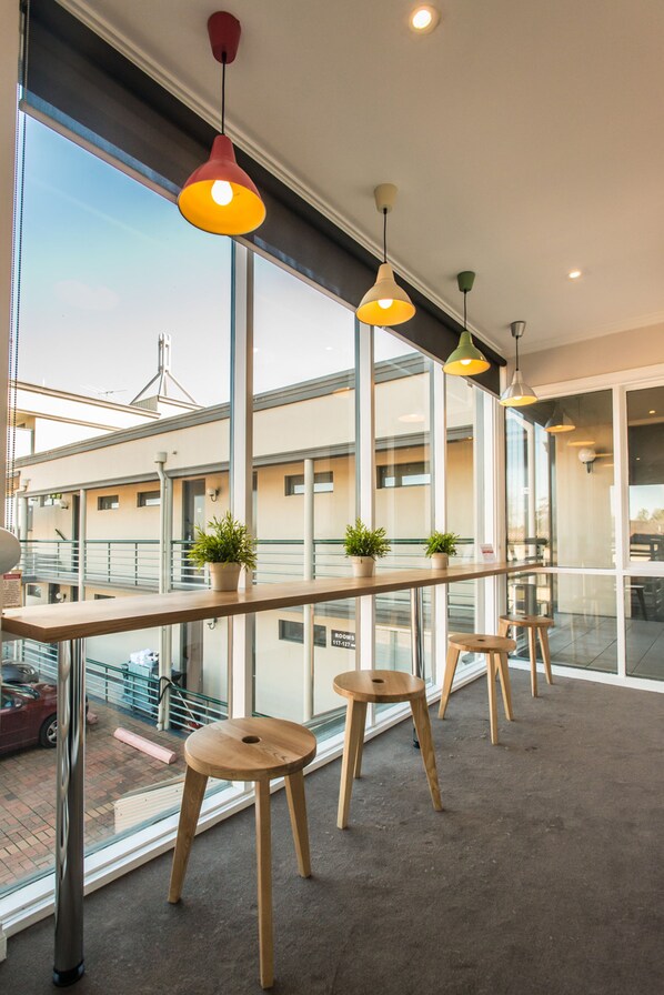 A modern interior with large windows, wooden stools, and potted plants.