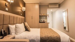 A hotel room with a bed, bedside tables, a wardrobe, a mirror, and wall-mounted lights.