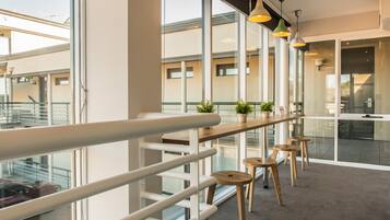 Ein moderner Arbeitsbereich mit Balkon, großen Fenstern und einem langen Tisch mit Hockstühlen.
