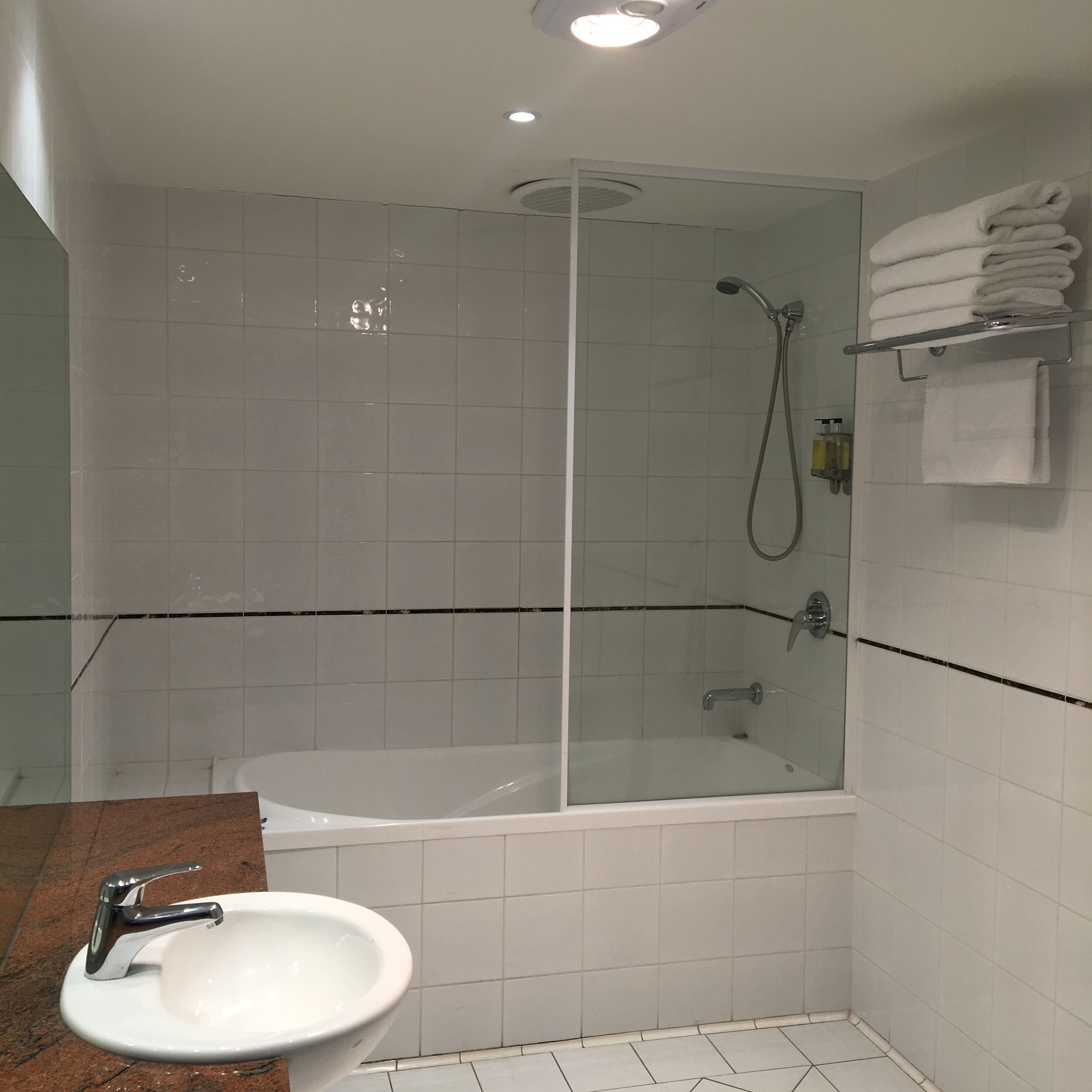 A modern bathroom with a glass-enclosed shower, a white bathtub, and a marble sink.
