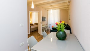 A modern living room with a dining table, chairs, a sofa, and a TV. - Villa Flores - Apartments (Dubrovnik)