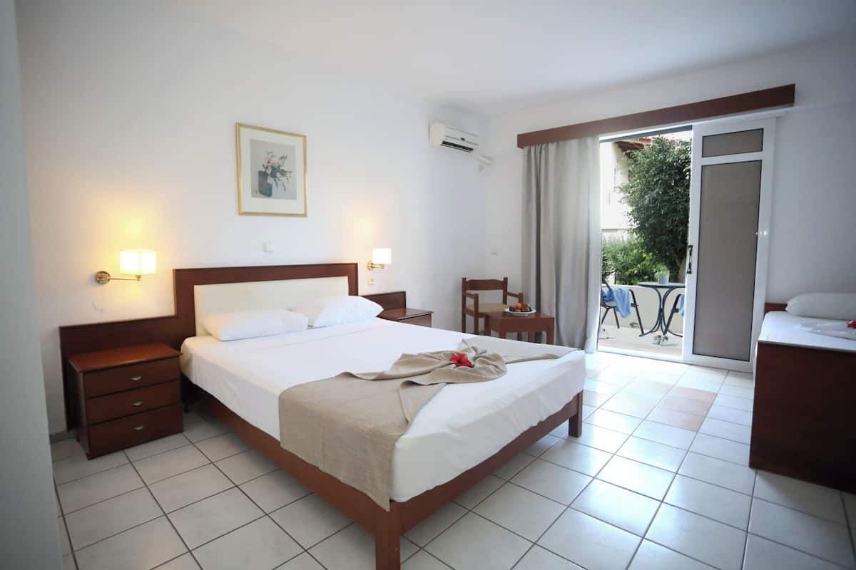A hotel room with a bed, bedside tables, a desk, a chair, and a balcony with a view.