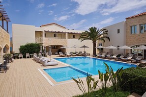 Zona de piscina con sillas de descanso, sombrillas y un edificio de piedra.