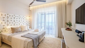 Una habitación de hotel moderna con una cama, un escritorio, un ventilador de techo y un ventanal con cortinas.