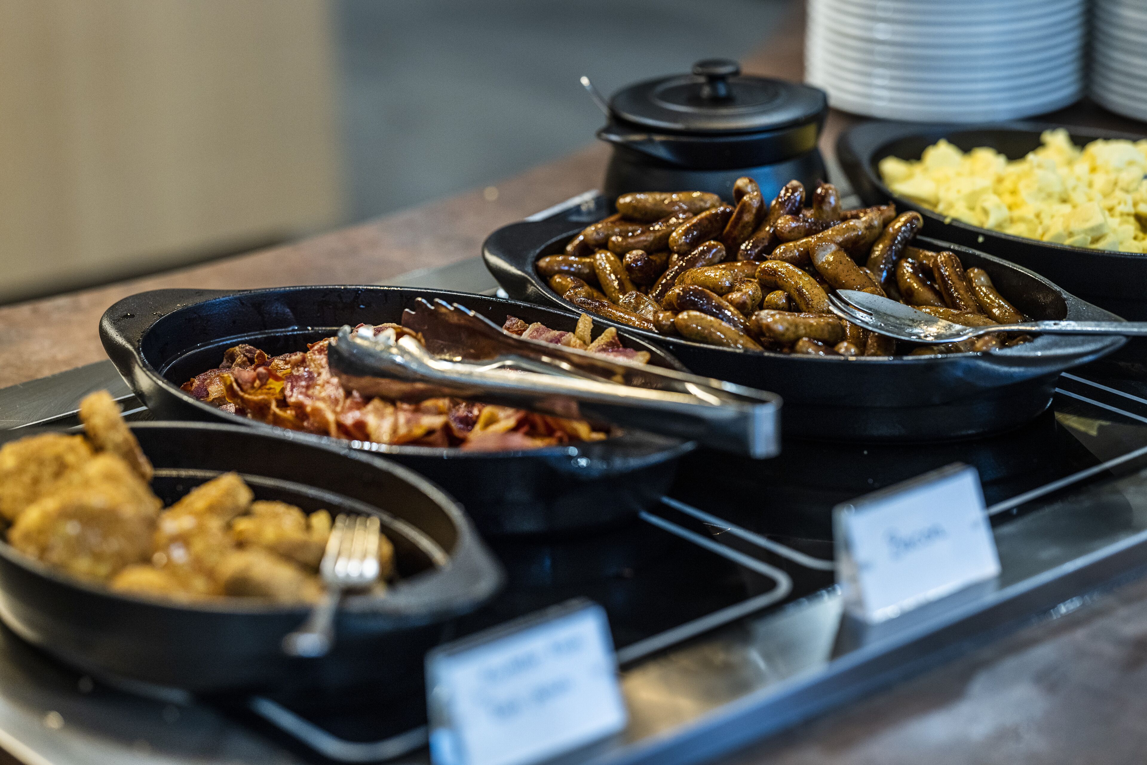 A buffet with various dishes including sausages, fried chicken, and scrambled eggs.