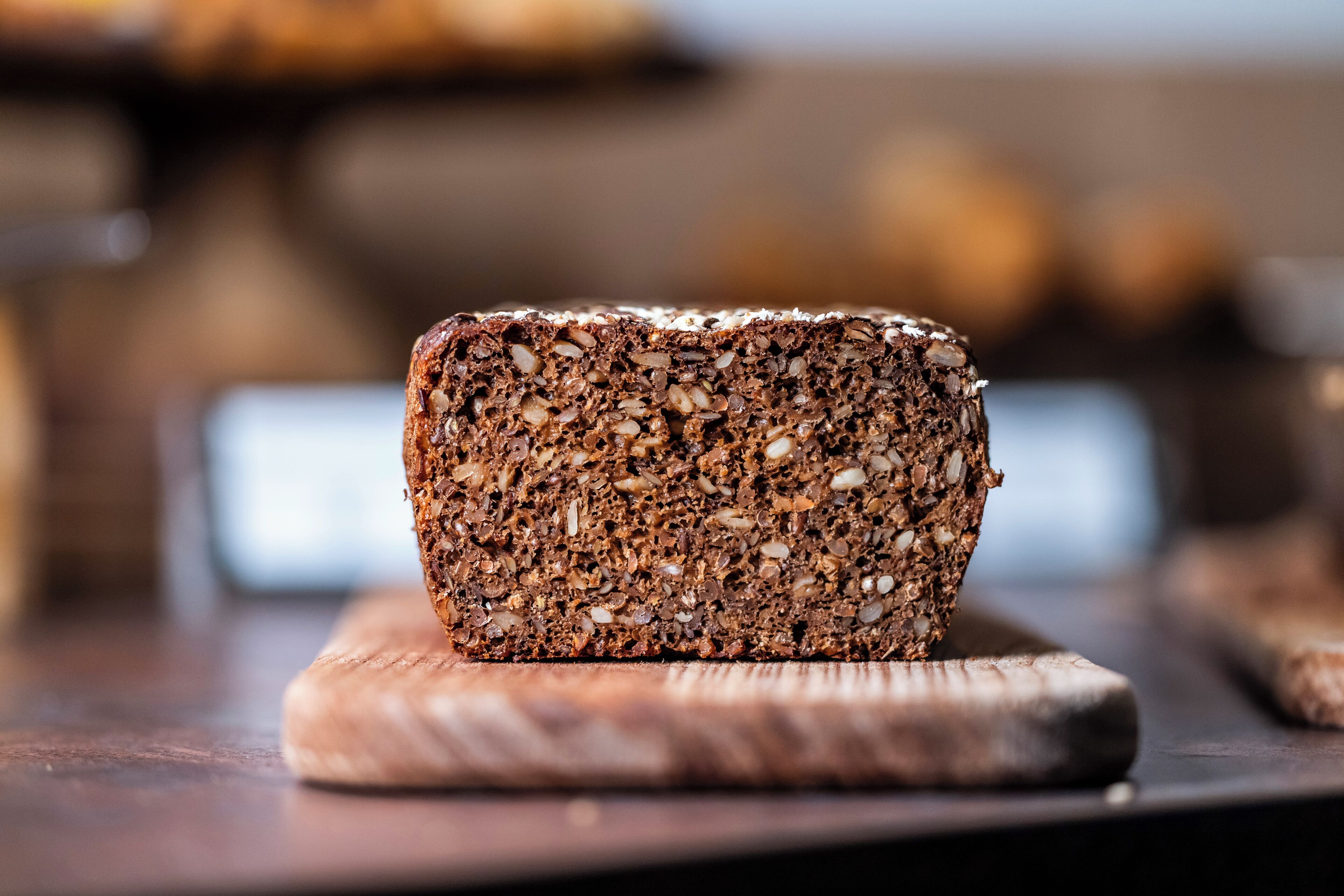 A loaf of multi-grain bread on a wooden cutting board.