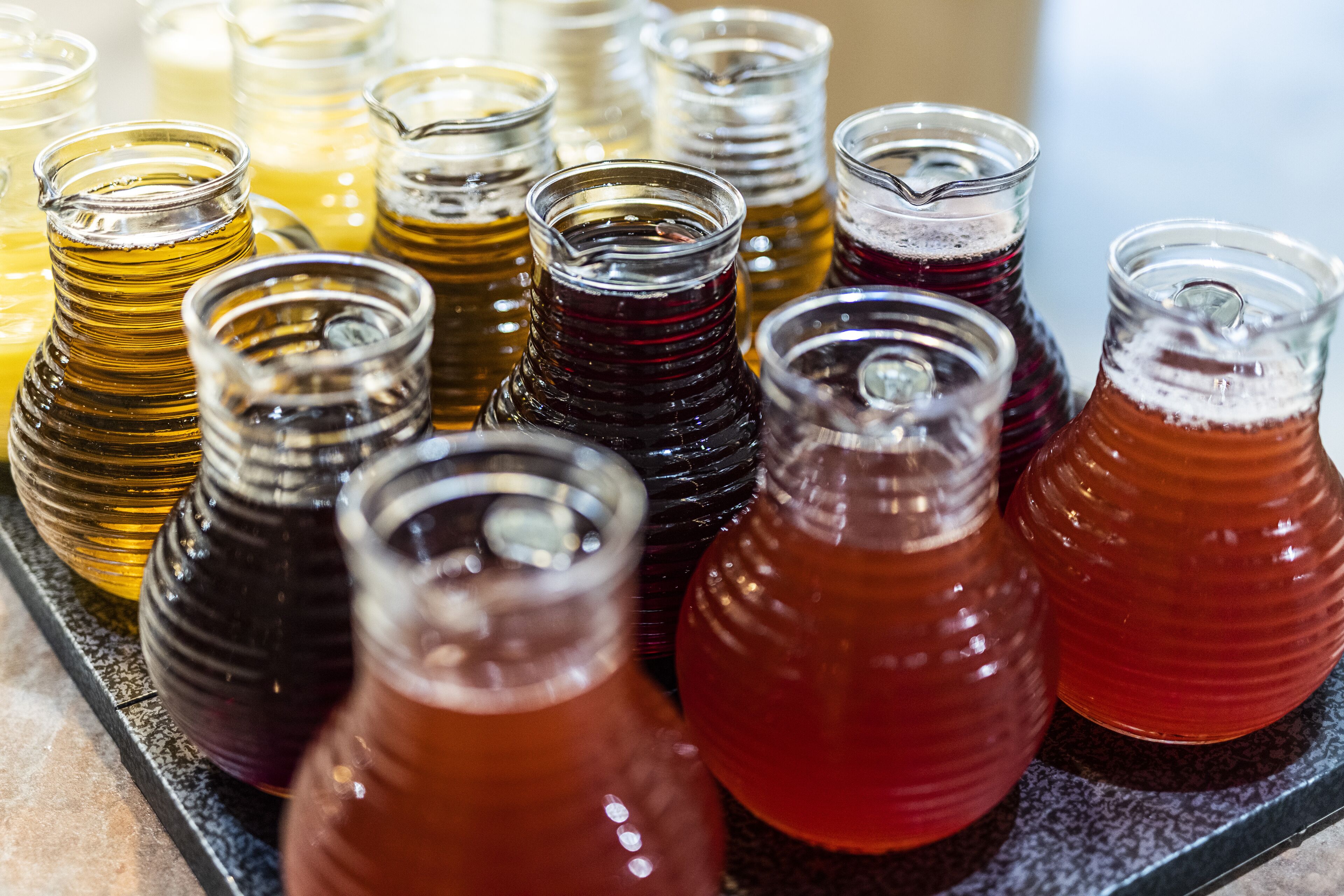 A variety of glass bottles with different colored liquids, likely containing beverages.