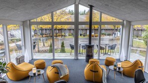 A modern indoor seating area with large windows, comfortable seating, and a fireplace.