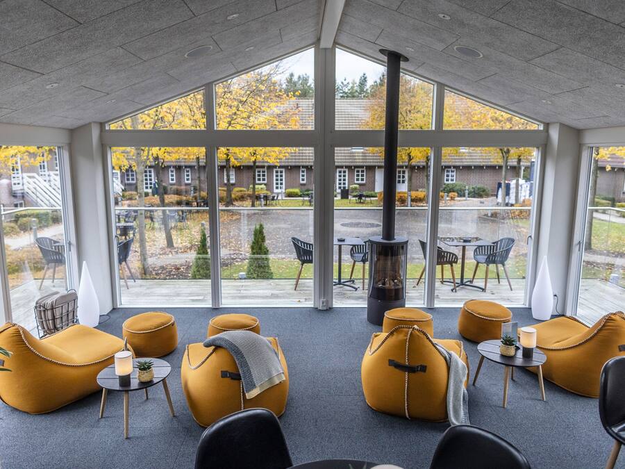 A modern indoor seating area with large windows, comfortable seating, and a fireplace.