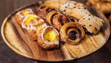 A wooden tray with various pastries, including croissants and rolls.