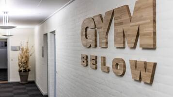 A hallway with a wall-mounted sign that reads "GYM BELOW".
