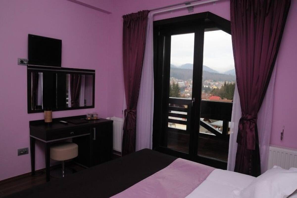 Une chambre à coucher avec un lit, un bureau, une chaise et une fenêtre avec des rideaux.