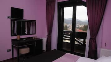 Un dormitorio con cama, escritorio, silla y ventana con cortinas.