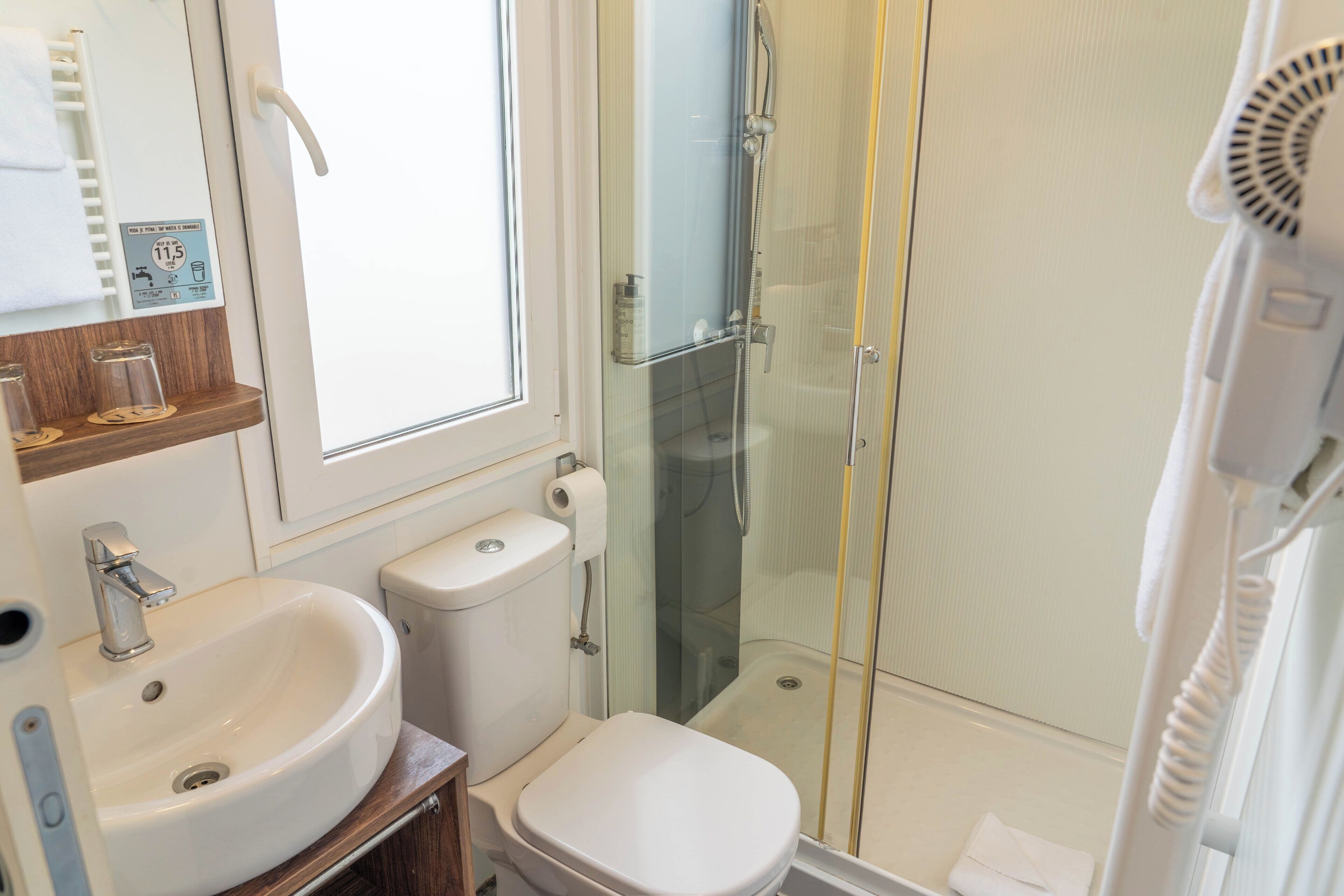 Une salle de bain équipée d’un lavabo, de toilettes et d’une douche à parois de verre.