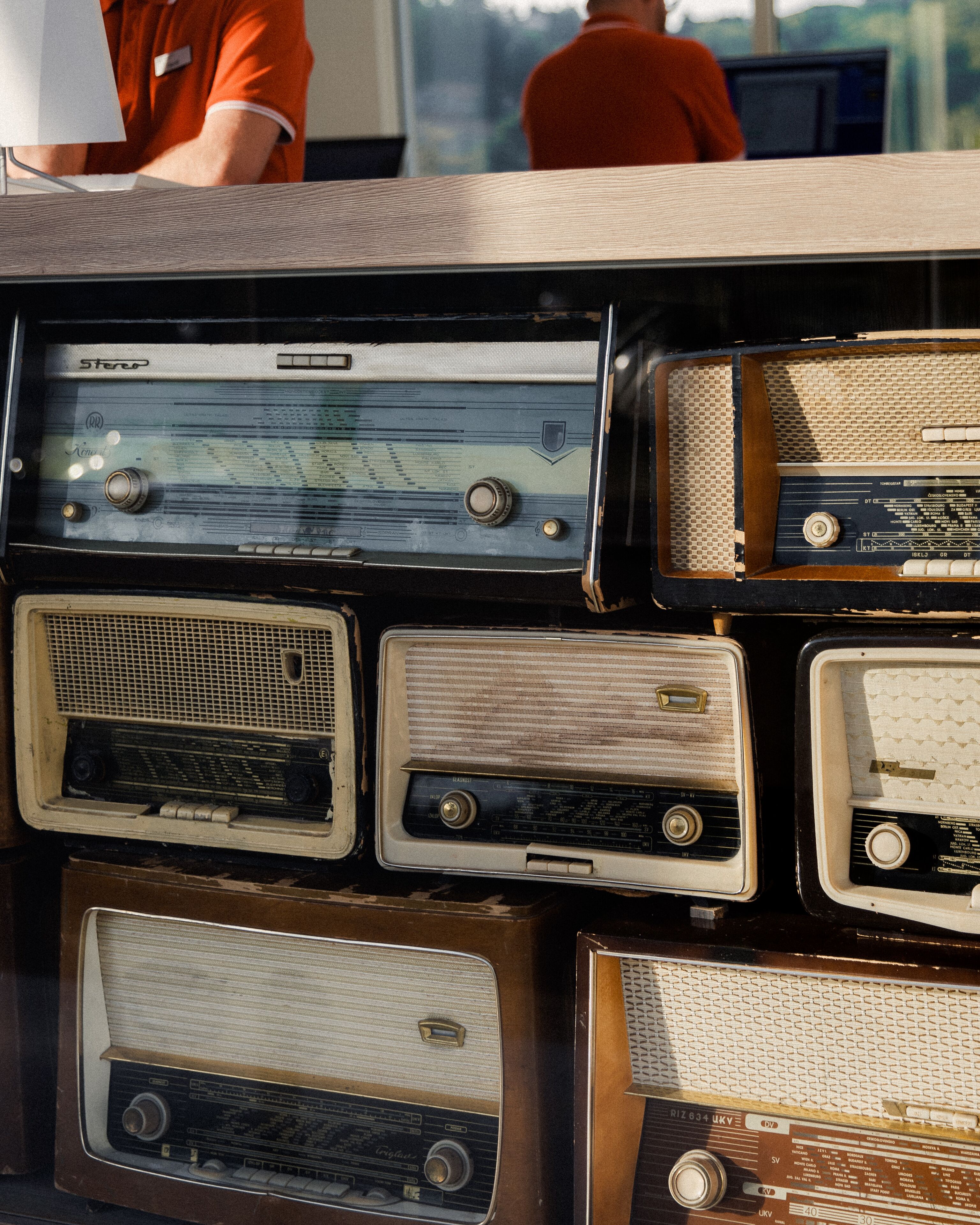 Une collection de radios anciennes, dotées de boutons de réglage et d’antennes, disposées en rangée.