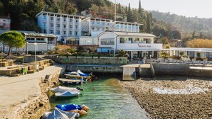 Ein Hotel am Wasser mit mehreren Balkonen, einer Strandbar und Booten, die an der Küste liegen.