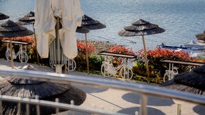 Ein Sitzbereich im Freien mit Sonnenschirmen, einem Fahrrad und Blick aufs Meer.