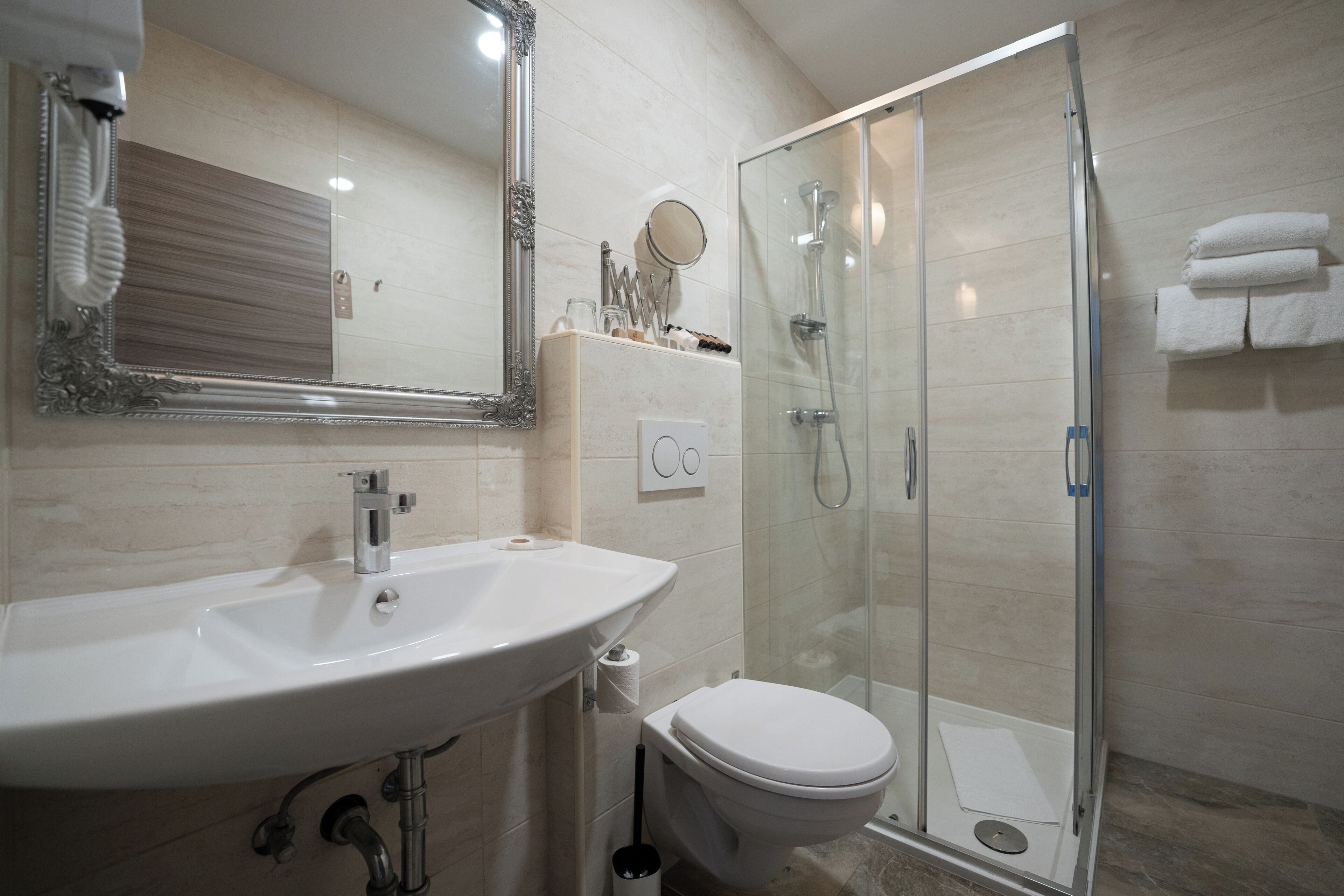 A bathroom with a sink, toilet, and glass-enclosed shower.