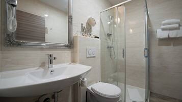 Un bagno con lavandino, WC e cabina doccia in vetro.